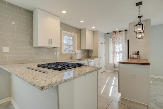 kitchen featuring sink, stainless steel dishwasher, kitchen peninsula, decorative light fixtures, and white cabinets