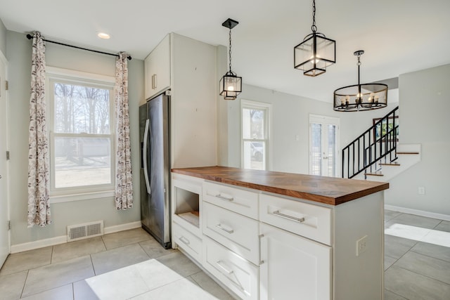 kitchen with wood counters, white cabinetry, and decorative light fixtures