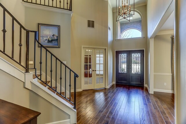 entryway featuring crown molding, french doors, dark wood-type flooring, and a high ceiling