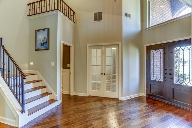 foyer featuring a towering ceiling, dark hardwood / wood-style flooring, and french doors