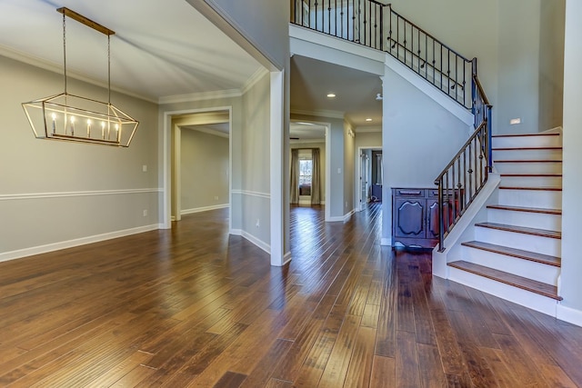 foyer featuring dark hardwood / wood-style flooring, crown molding, and an inviting chandelier