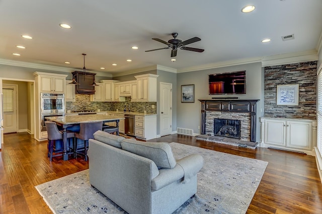 living room with ceiling fan, ornamental molding, a fireplace, and hardwood / wood-style flooring