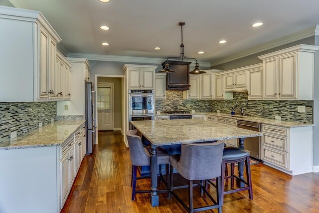 kitchen featuring light stone counters, pendant lighting, a center island, and stainless steel appliances