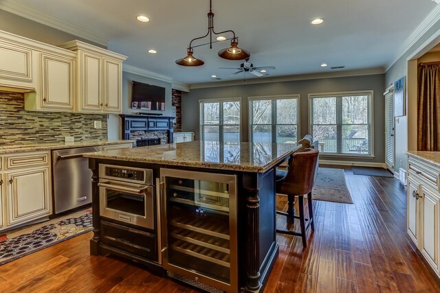 kitchen with wine cooler, ceiling fan, appliances with stainless steel finishes, light stone counters, and cream cabinets