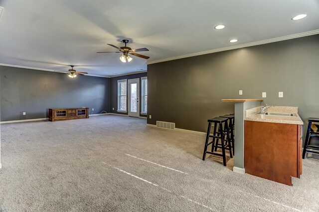 carpeted living room featuring ceiling fan, sink, and crown molding