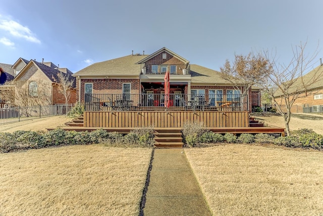 view of front facade with a balcony, a wooden deck, and a front yard