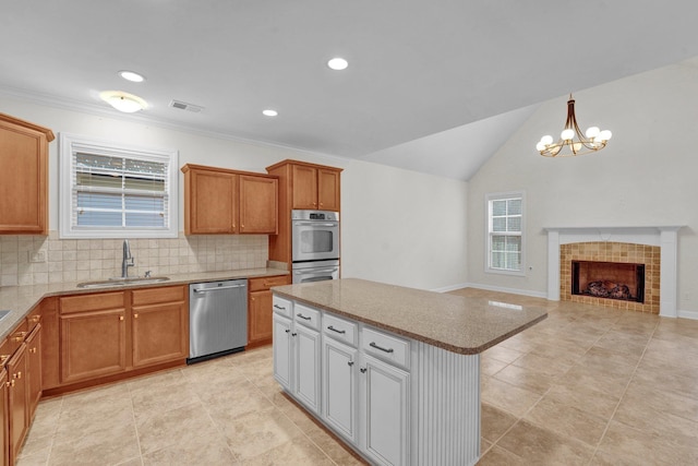 kitchen with a tile fireplace, sink, a center island, stainless steel dishwasher, and lofted ceiling