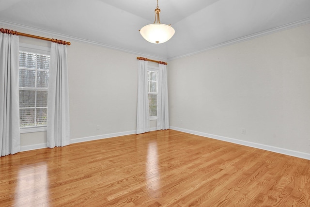 unfurnished room featuring vaulted ceiling, ornamental molding, and light hardwood / wood-style flooring