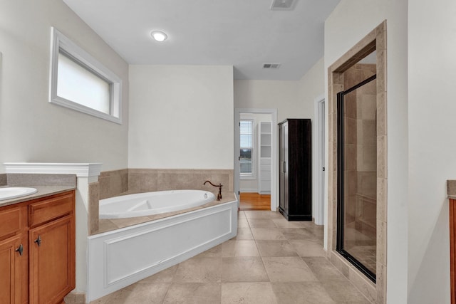 bathroom with independent shower and bath, tile patterned flooring, vanity, and a healthy amount of sunlight