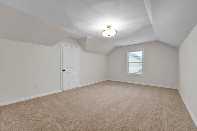 bonus room with light colored carpet and vaulted ceiling