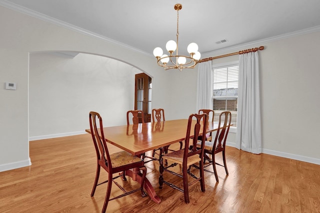 dining room with light hardwood / wood-style flooring, crown molding, and a notable chandelier