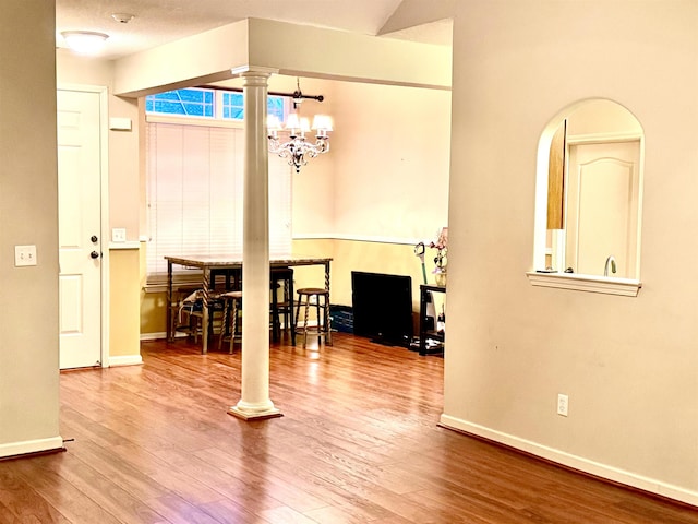 interior space featuring ornate columns, wood-type flooring, a textured ceiling, and a chandelier