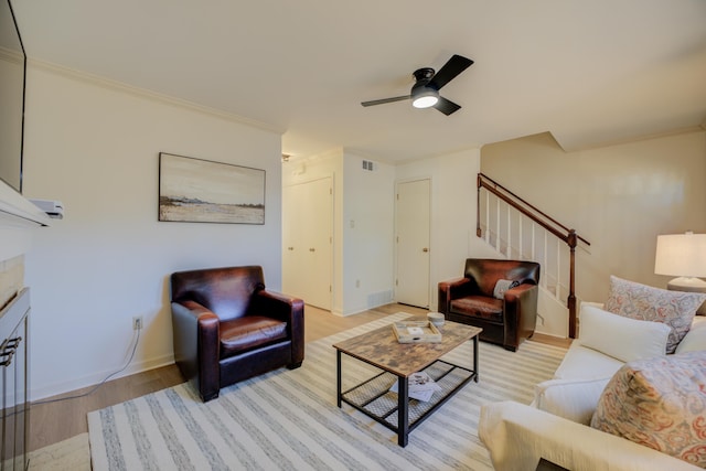 living room featuring ceiling fan, light hardwood / wood-style floors, and crown molding