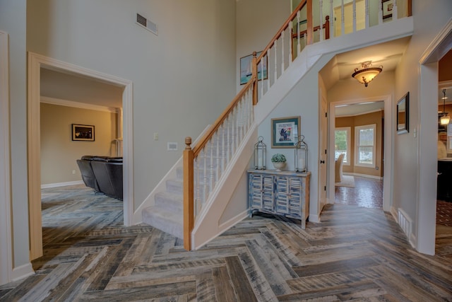 staircase featuring a towering ceiling and parquet flooring