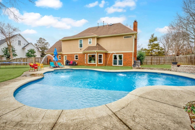 view of pool featuring a yard, a trampoline, pool water feature, a water slide, and a patio