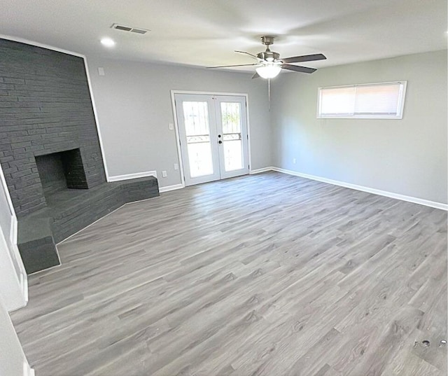 unfurnished living room featuring a fireplace, french doors, ceiling fan, and a healthy amount of sunlight