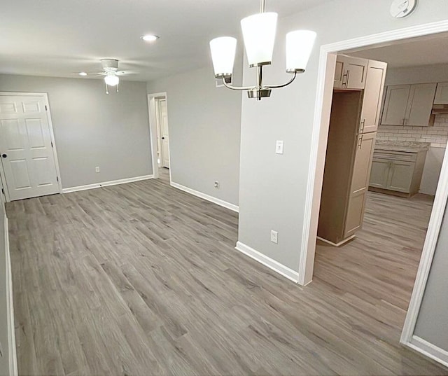 unfurnished dining area with light hardwood / wood-style flooring and ceiling fan with notable chandelier