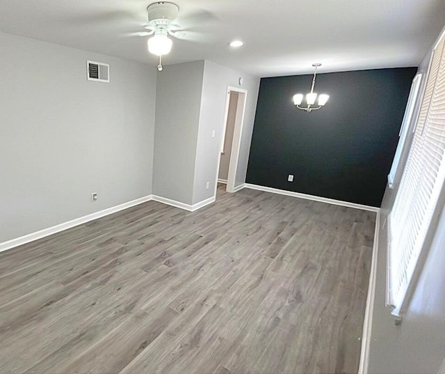 spare room with hardwood / wood-style flooring and ceiling fan with notable chandelier