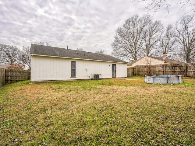 rear view of property featuring a yard, a covered pool, and cooling unit
