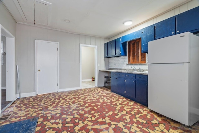 kitchen featuring blue cabinetry, white fridge, tasteful backsplash, and sink