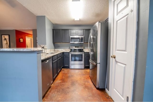 kitchen with gray cabinets, a textured ceiling, concrete flooring, kitchen peninsula, and stainless steel appliances