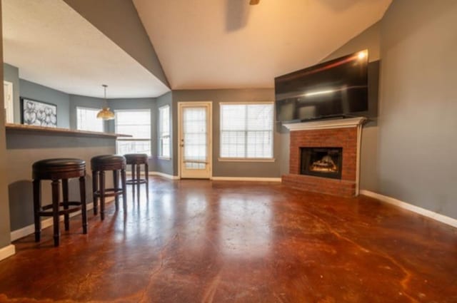 living room featuring ceiling fan, vaulted ceiling, and a brick fireplace