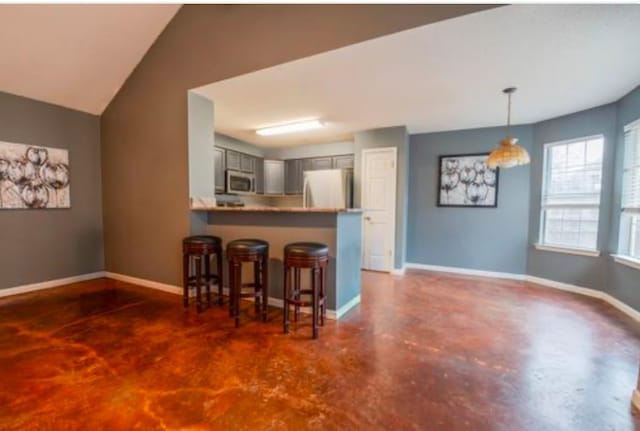 kitchen with kitchen peninsula, a kitchen bar, decorative light fixtures, gray cabinets, and white fridge