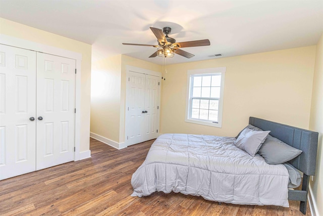 bedroom featuring multiple closets, ceiling fan, and dark hardwood / wood-style floors