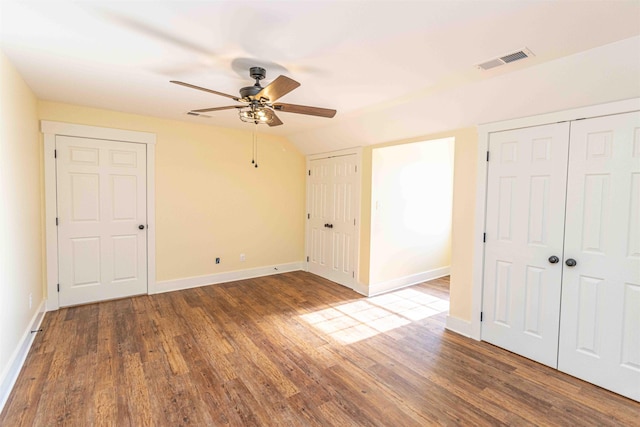 unfurnished bedroom featuring vaulted ceiling, ceiling fan, two closets, and hardwood / wood-style flooring