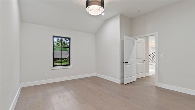 empty room featuring light wood-type flooring and vaulted ceiling