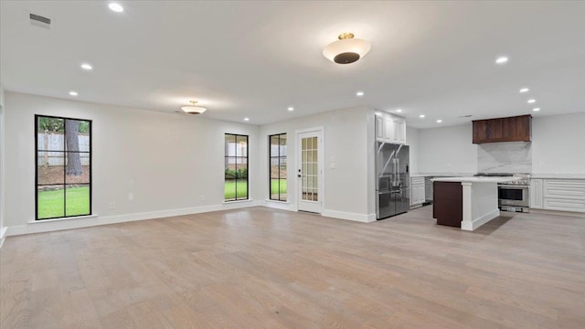 kitchen with backsplash, stainless steel fridge, plenty of natural light, and a kitchen island