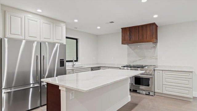 kitchen featuring a center island, sink, light wood-type flooring, light stone countertops, and appliances with stainless steel finishes