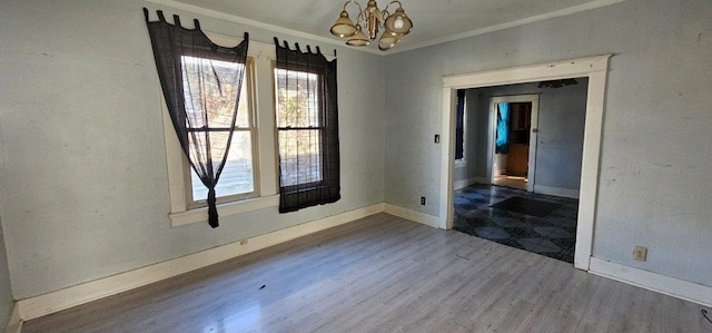 empty room with dark hardwood / wood-style flooring, crown molding, and a chandelier