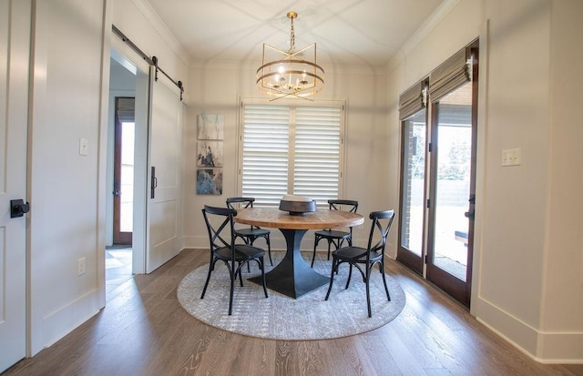 dining area featuring hardwood / wood-style floors, a barn door, an inviting chandelier, and crown molding