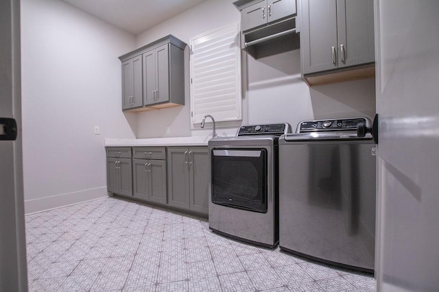 clothes washing area with washer and clothes dryer, cabinets, and sink