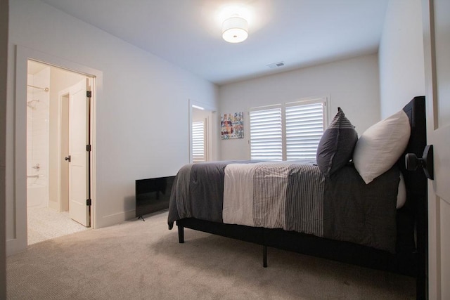 bedroom with ensuite bathroom and light colored carpet