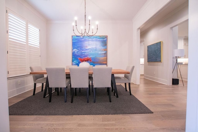 dining space with wood-type flooring, a notable chandelier, and ornamental molding