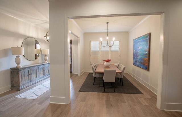 dining room featuring wood-type flooring, crown molding, and a notable chandelier