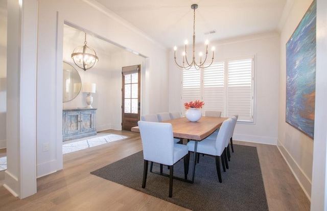 dining space featuring wood-type flooring, a notable chandelier, and ornamental molding