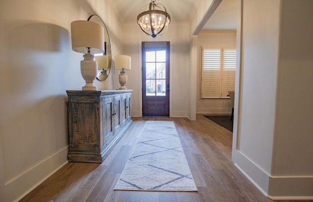 entryway featuring crown molding, a notable chandelier, and hardwood / wood-style flooring