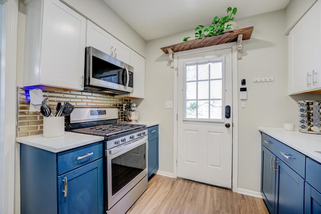 kitchen with decorative backsplash, white cabinetry, blue cabinets, and appliances with stainless steel finishes