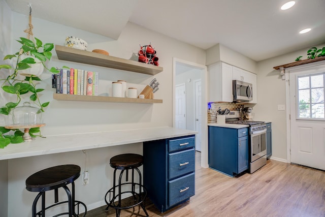 kitchen featuring appliances with stainless steel finishes, a kitchen breakfast bar, tasteful backsplash, blue cabinetry, and white cabinets