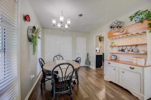 dining area with dark hardwood / wood-style floors and an inviting chandelier