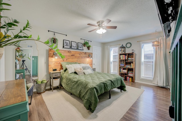 bedroom with hardwood / wood-style floors, a textured ceiling, and ceiling fan