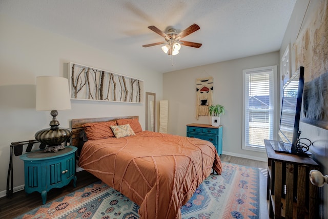 bedroom featuring ceiling fan, dark hardwood / wood-style floors, and a textured ceiling