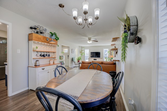 dining room featuring a textured ceiling, dark wood-type flooring, and ceiling fan with notable chandelier