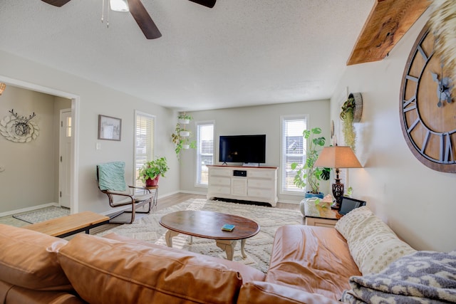 living room with ceiling fan, a textured ceiling, and light wood-type flooring