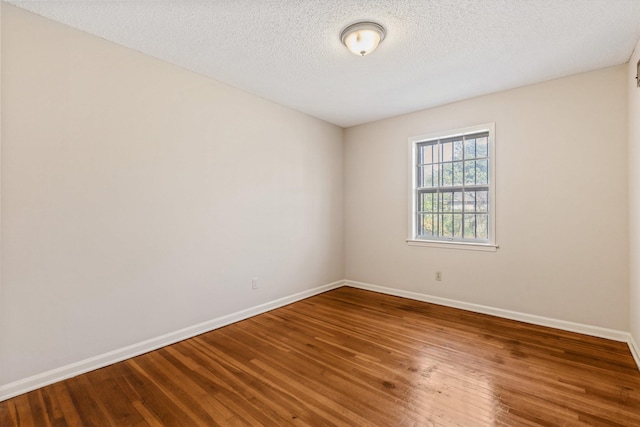 spare room with a textured ceiling and hardwood / wood-style flooring