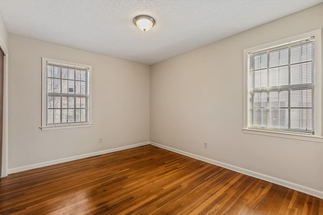 unfurnished room with dark hardwood / wood-style flooring and a textured ceiling