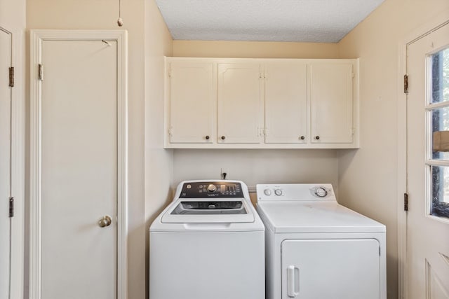 washroom with cabinets, a textured ceiling, and washing machine and clothes dryer